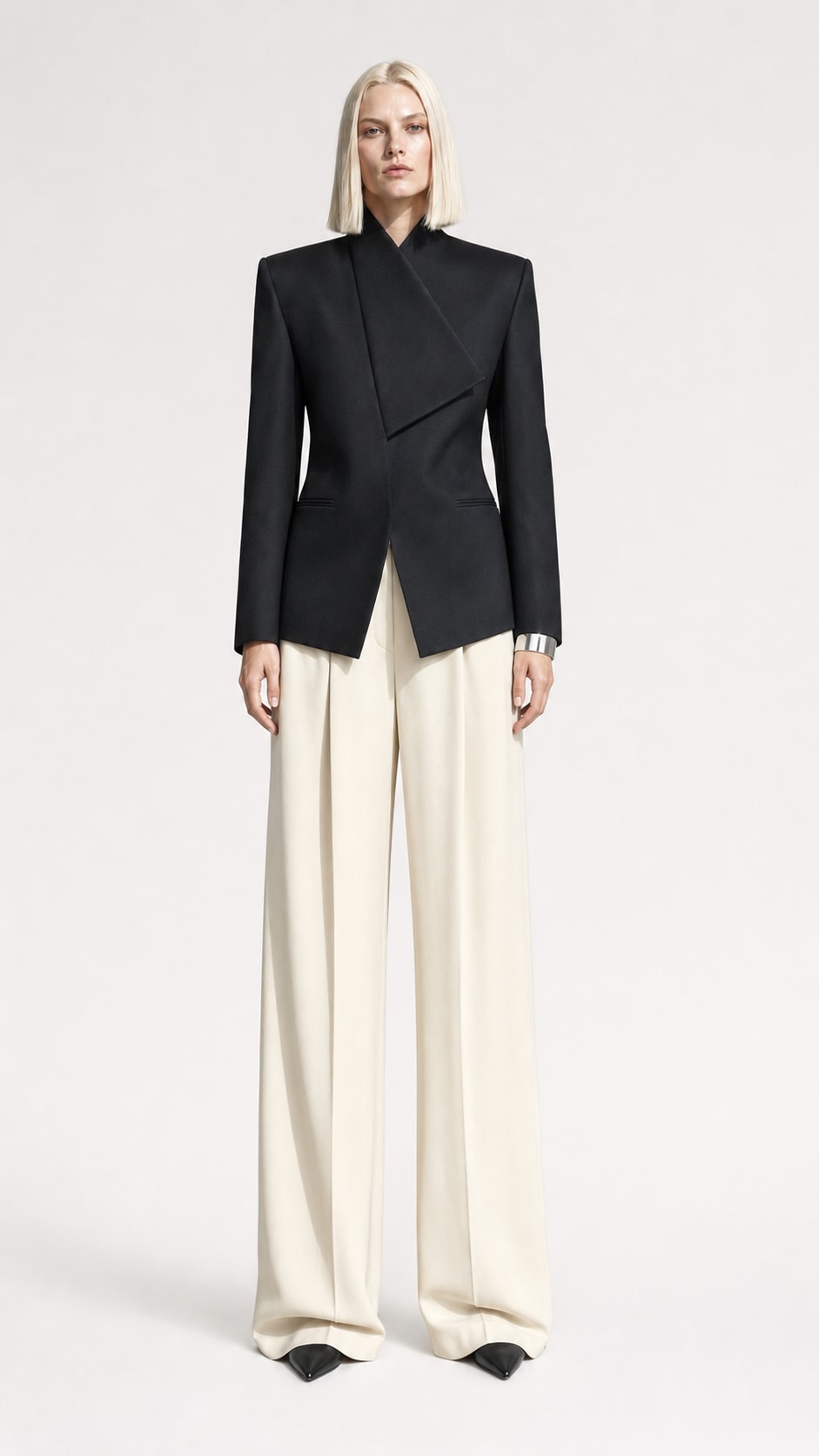 Fictional blonde fashion model in sculptural tailoring inside a concrete studio