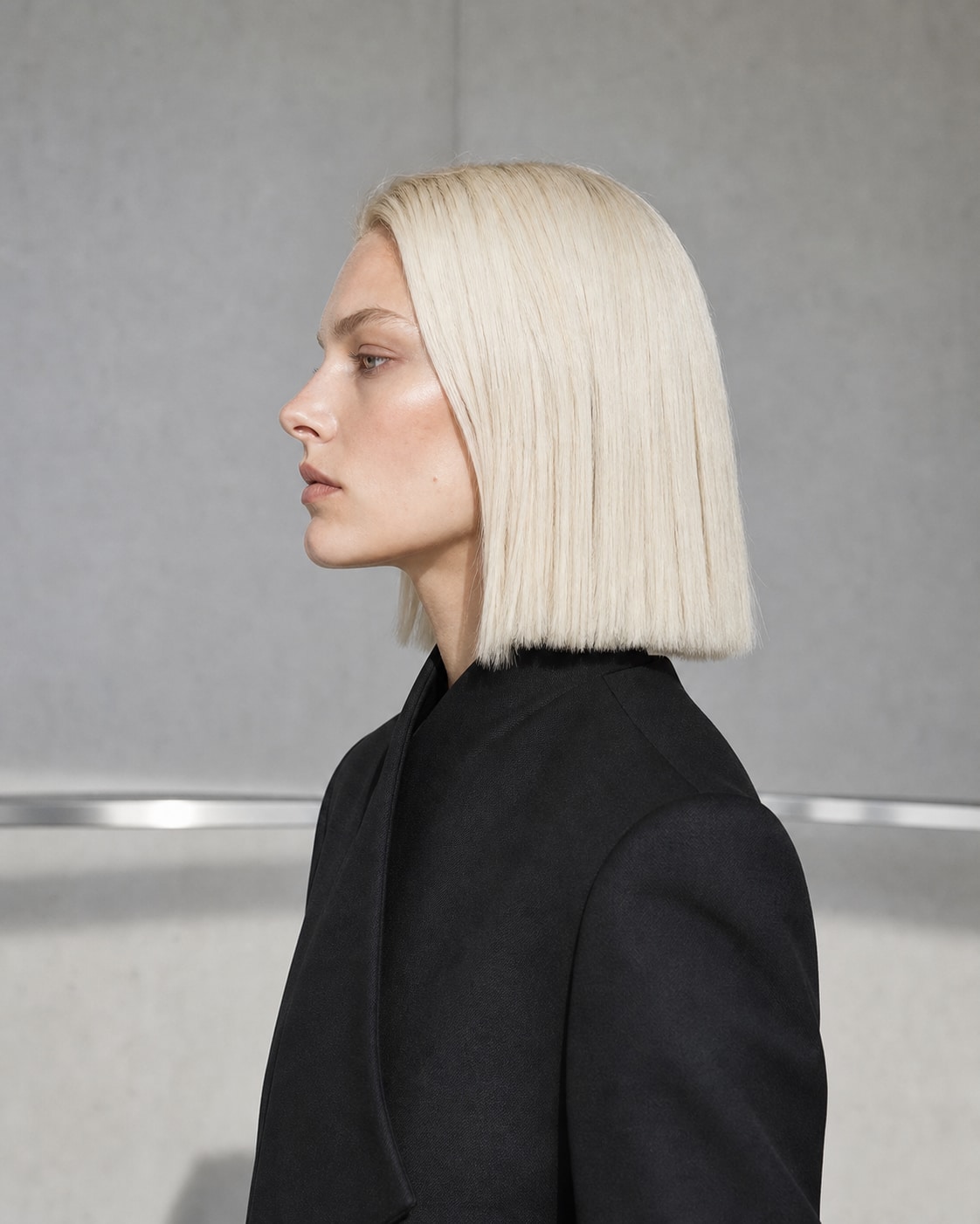 Fictional blonde fashion model in sculptural tailoring inside a concrete studio